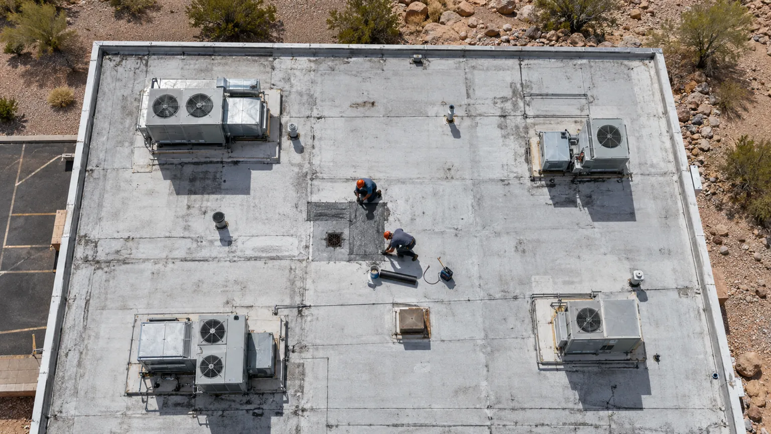Overhead view of a white flat commercial roof with rooftop units and a patch area