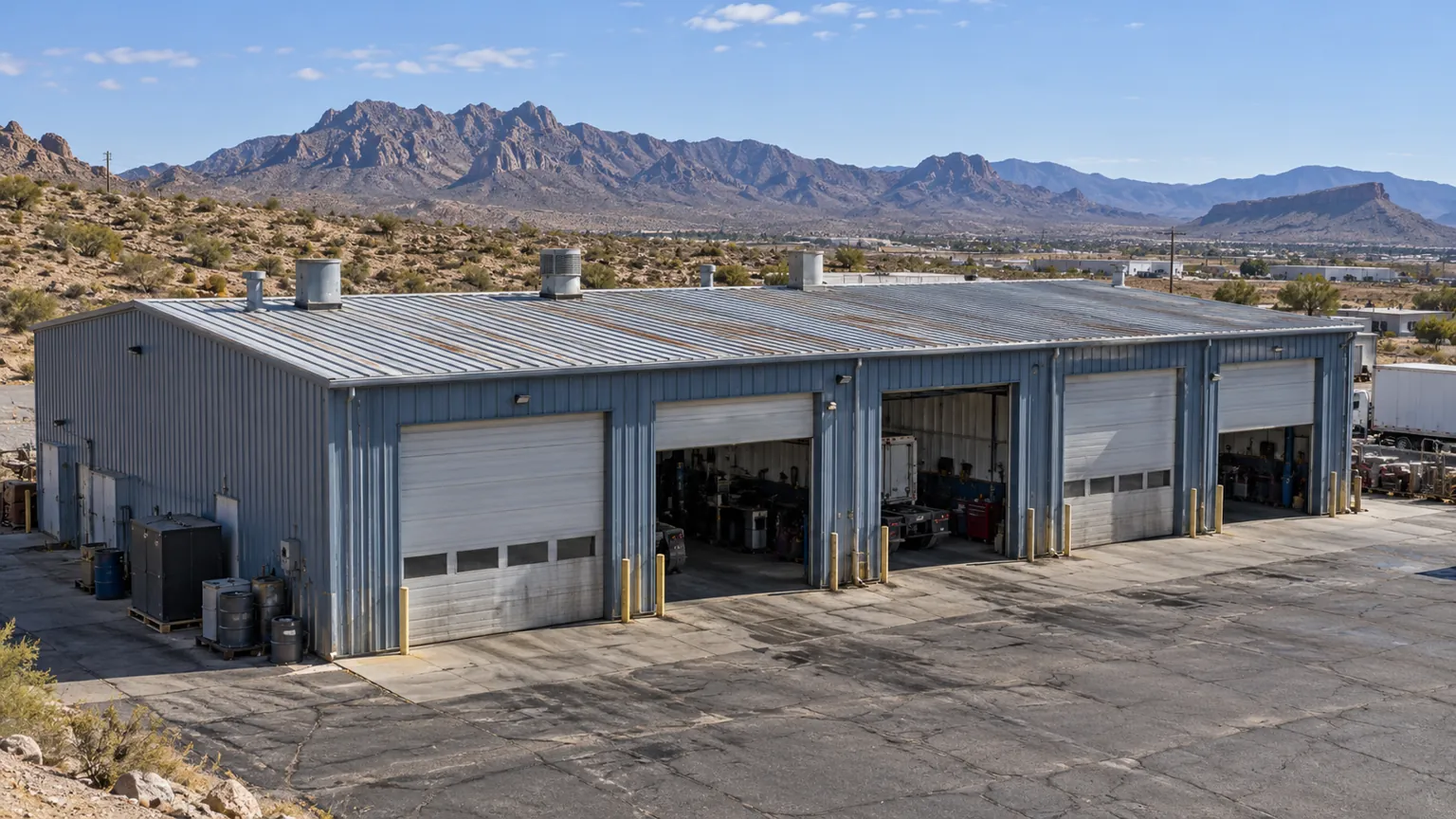 Steel shop with roll-up doors and a metal roof on a desert lot west of Kingman